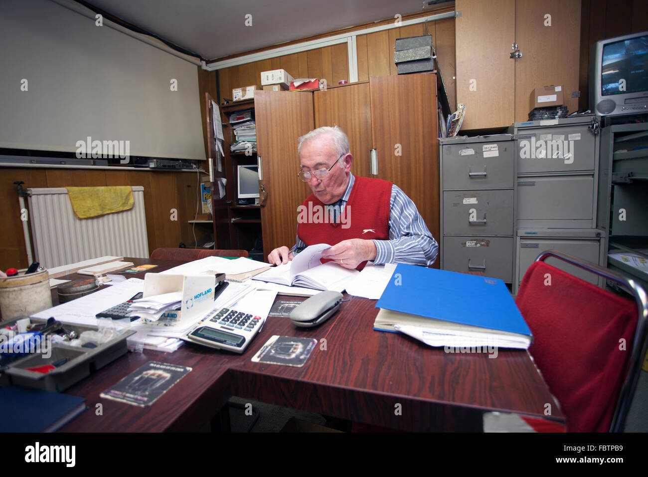 Un homme travaillant sur des comptes ouverts dans un style rétro à la bureau. Banque D'Images