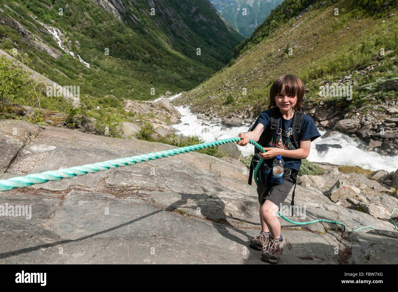 Garçon utilise corde au passage raide, rock, un chemin de randonnée vers le  glacier, Buarbreen river valley stream en bas pour fjord en arrière-plan  Photo Stock - Alamy