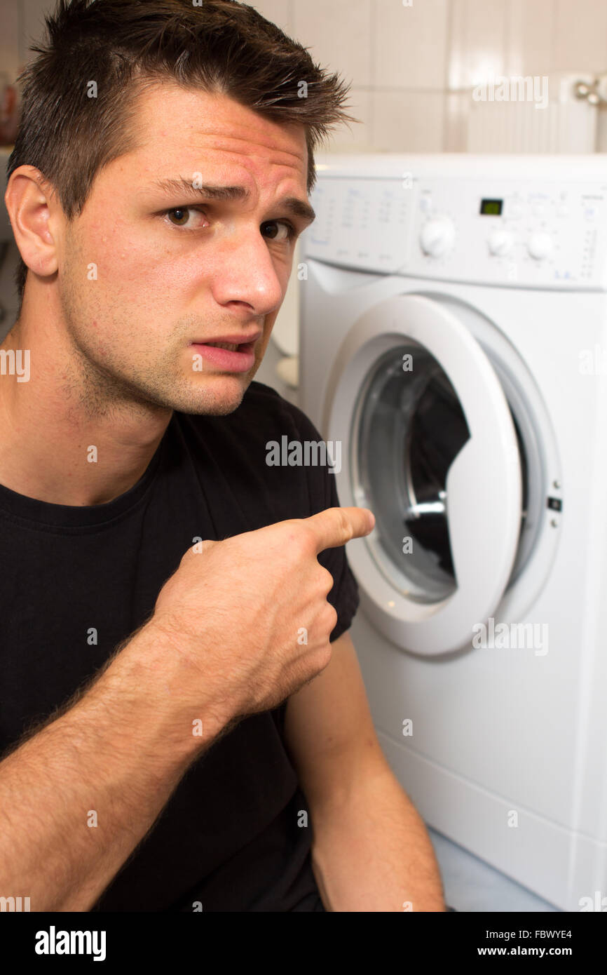 Jeune homme malheureux avec lave linge Banque D'Images