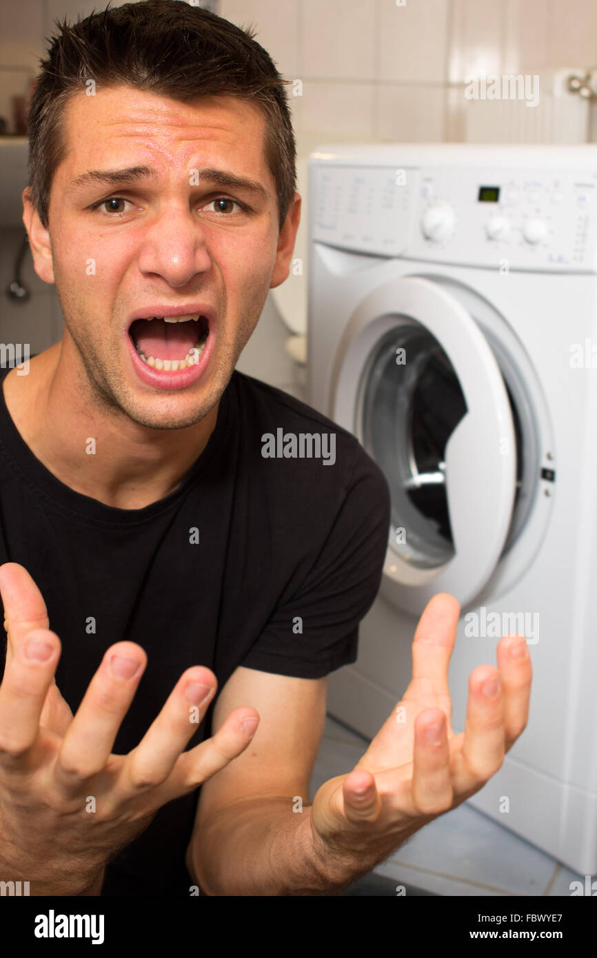 Jeune homme malheureux avec lave linge Banque D'Images