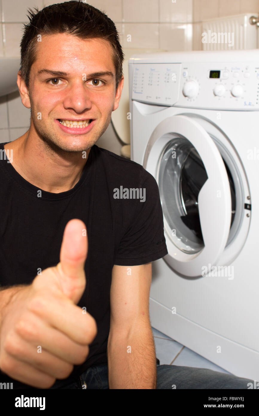 Jeune homme heureux avec lave linge Banque D'Images