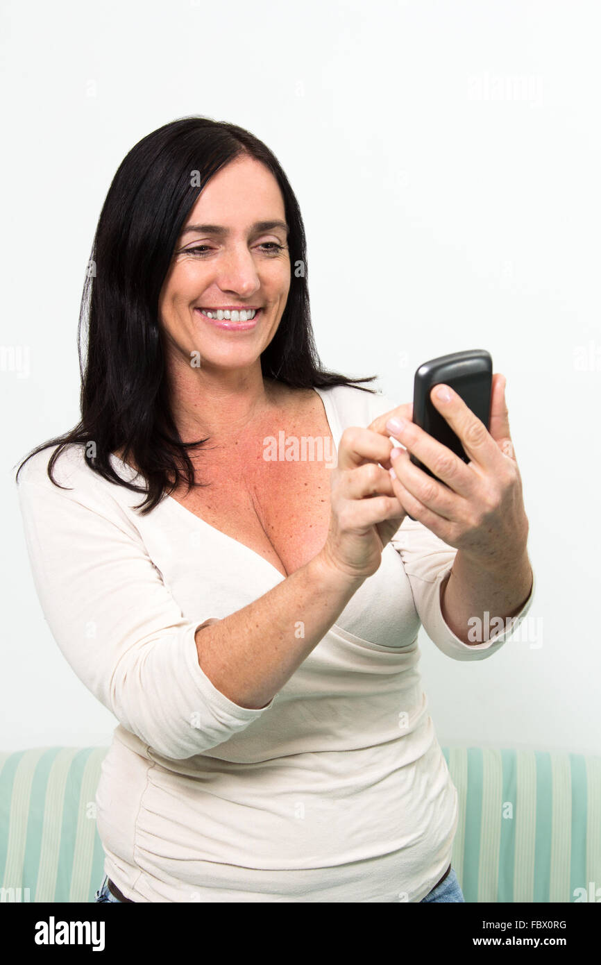 Dark haired woman en utilisant un smartphone Banque D'Images