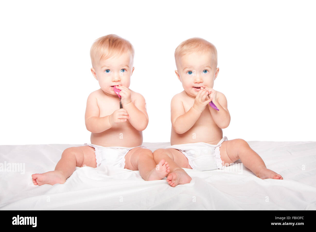 Les jumeaux mignons bébés avec cuillères Banque D'Images
