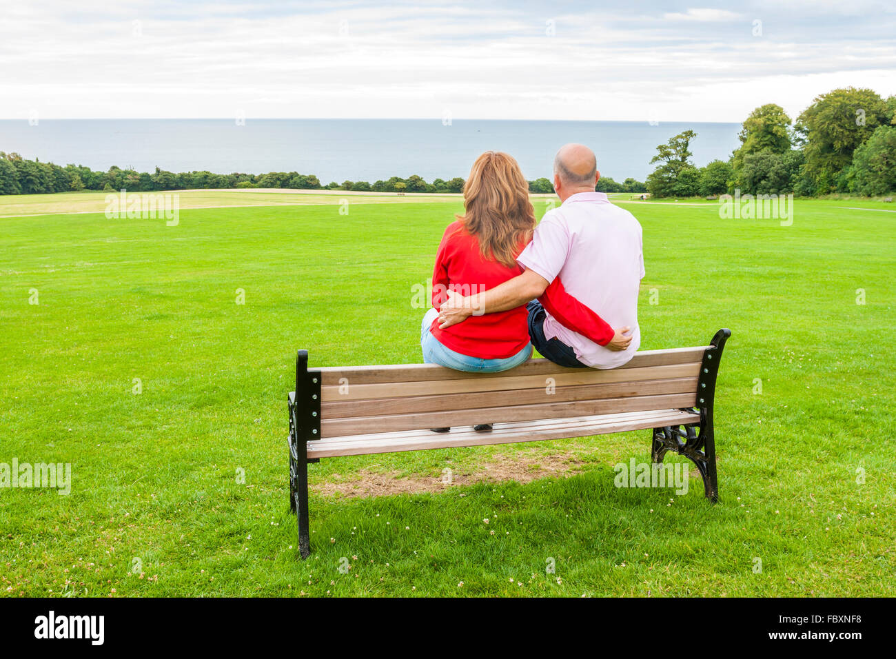 Vue arrière du moyen age couple assis sur un banc face à la mer Banque D'Images