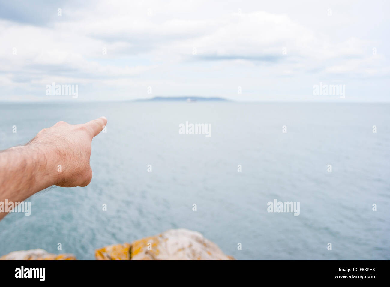 Pointer du doigt une île à l'horizon sur la mer Banque D'Images