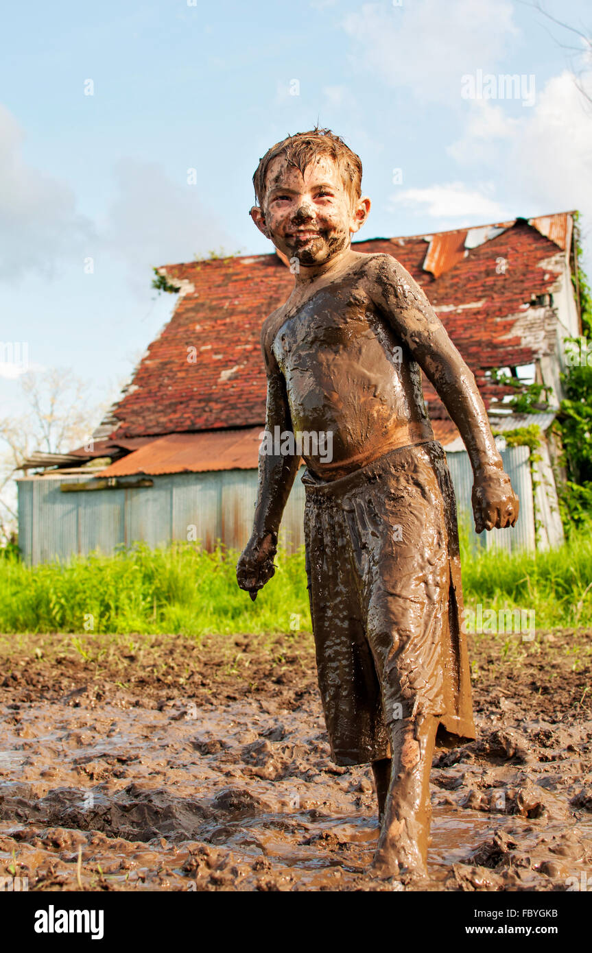 Jeune garçon souriant et couvert de boue Banque D'Images