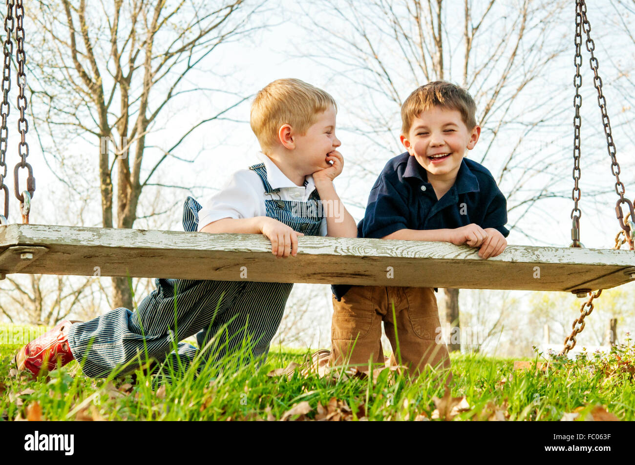 Deux garçons s'appuyant sur swing rire ensemble Banque D'Images
