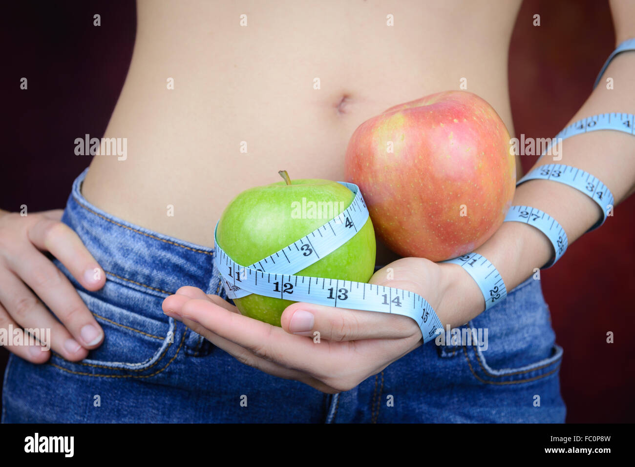 Femme asiatique slim , portant des jeans, porte des pommes fraîches et ruban à mesurer dans la main Banque D'Images