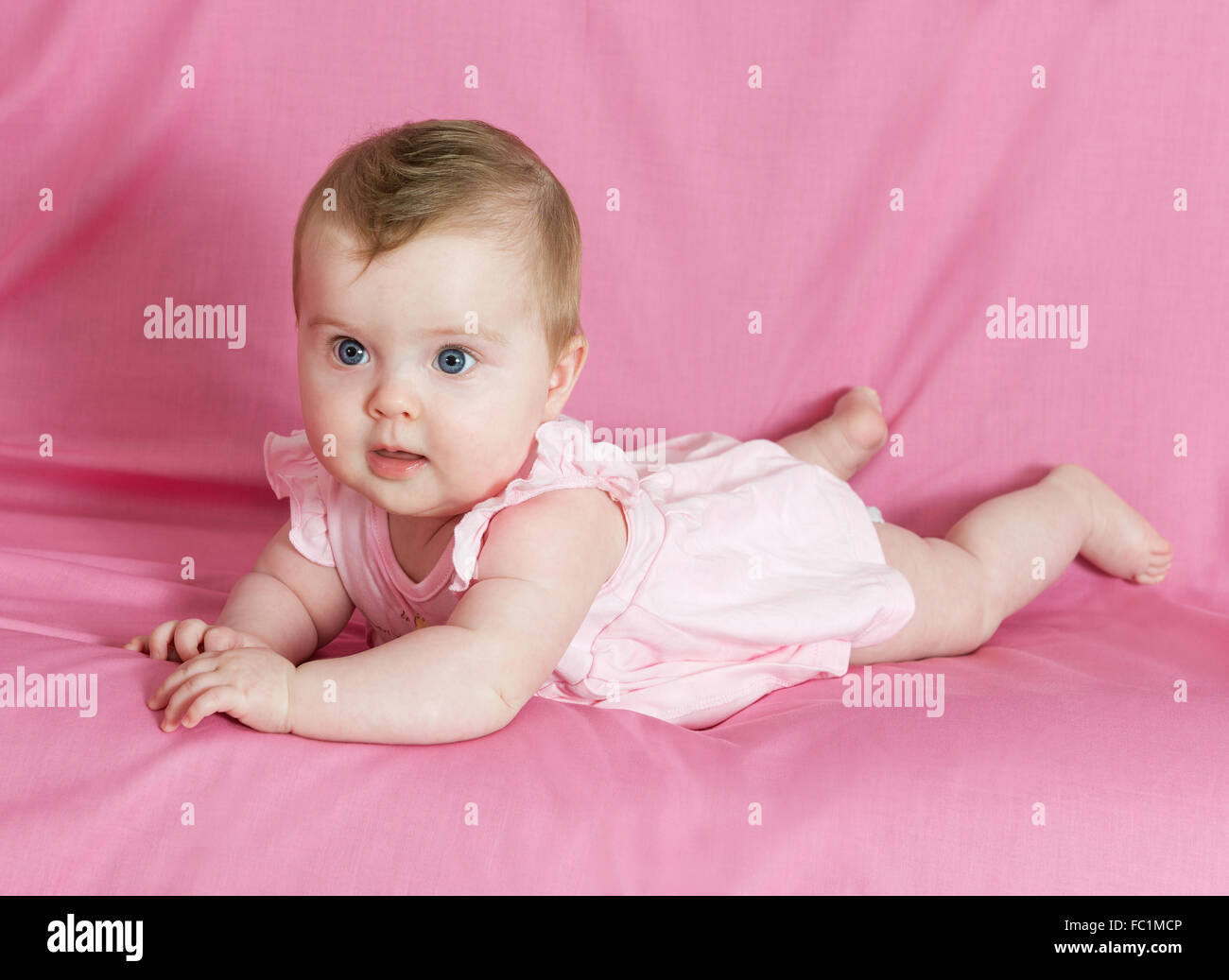 Adorable happy baby girl sur fond rose Banque D'Images