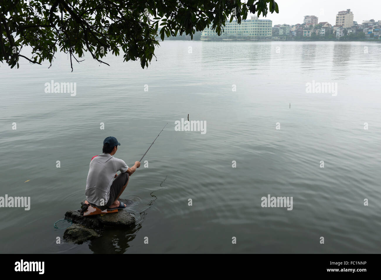 L'homme pêche dans le lac de l'Ouest près de la Pagode Tran Quoc, Hanoi, Vietnam Banque D'Images