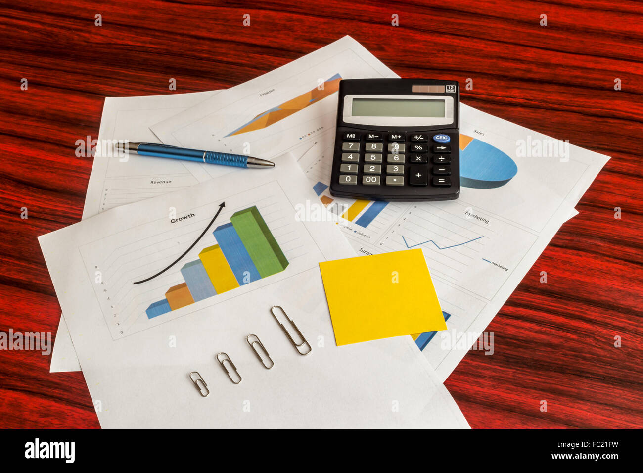 Groupe d'impression de graphiques avec calculatrice, trombones, note jaune et un stylo sur eux Banque D'Images