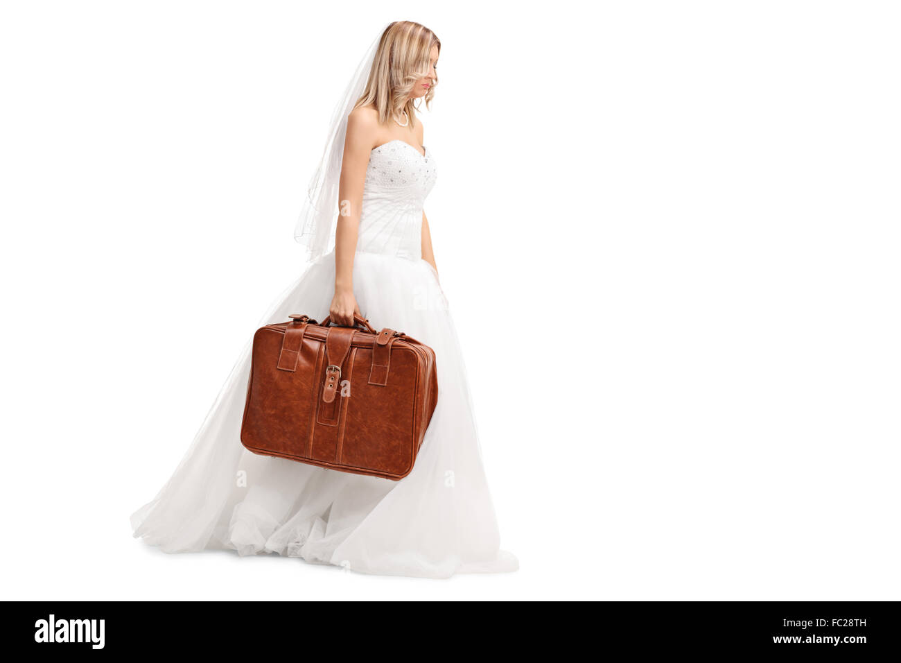 Triste jeune mariée dans une robe de mariée blanche la marche et tenant une valise marron isolé sur fond blanc Banque D'Images