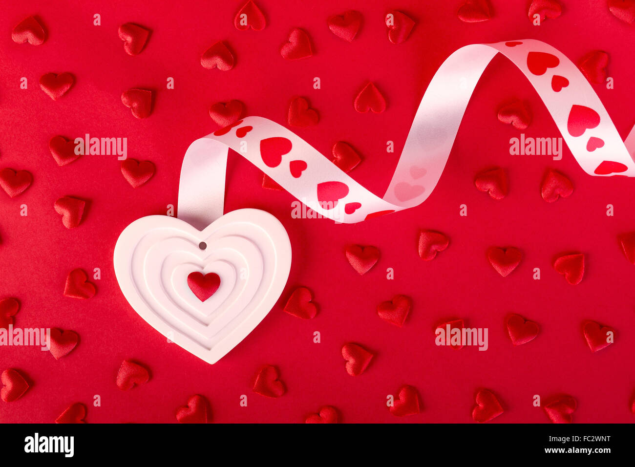 Blanc forme coeur avec du ruban et des coeurs rouges sur fond rouge. Valentines Day concept. Banque D'Images