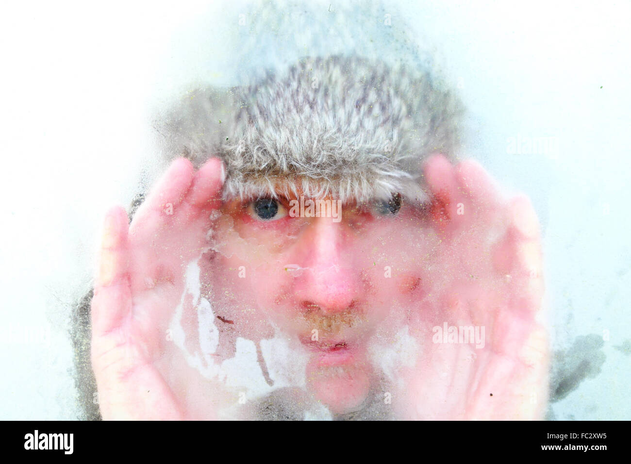 Hiver froid avec l'homme à la toque de fourrure par fenêtre avec condensation congelé Banque D'Images