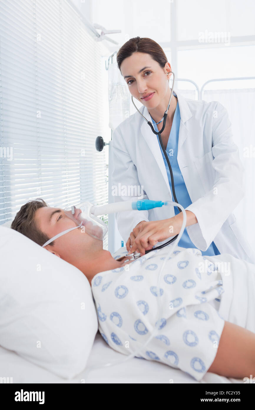 Smiling doctor auscultating ses patients poitrine Banque D'Images