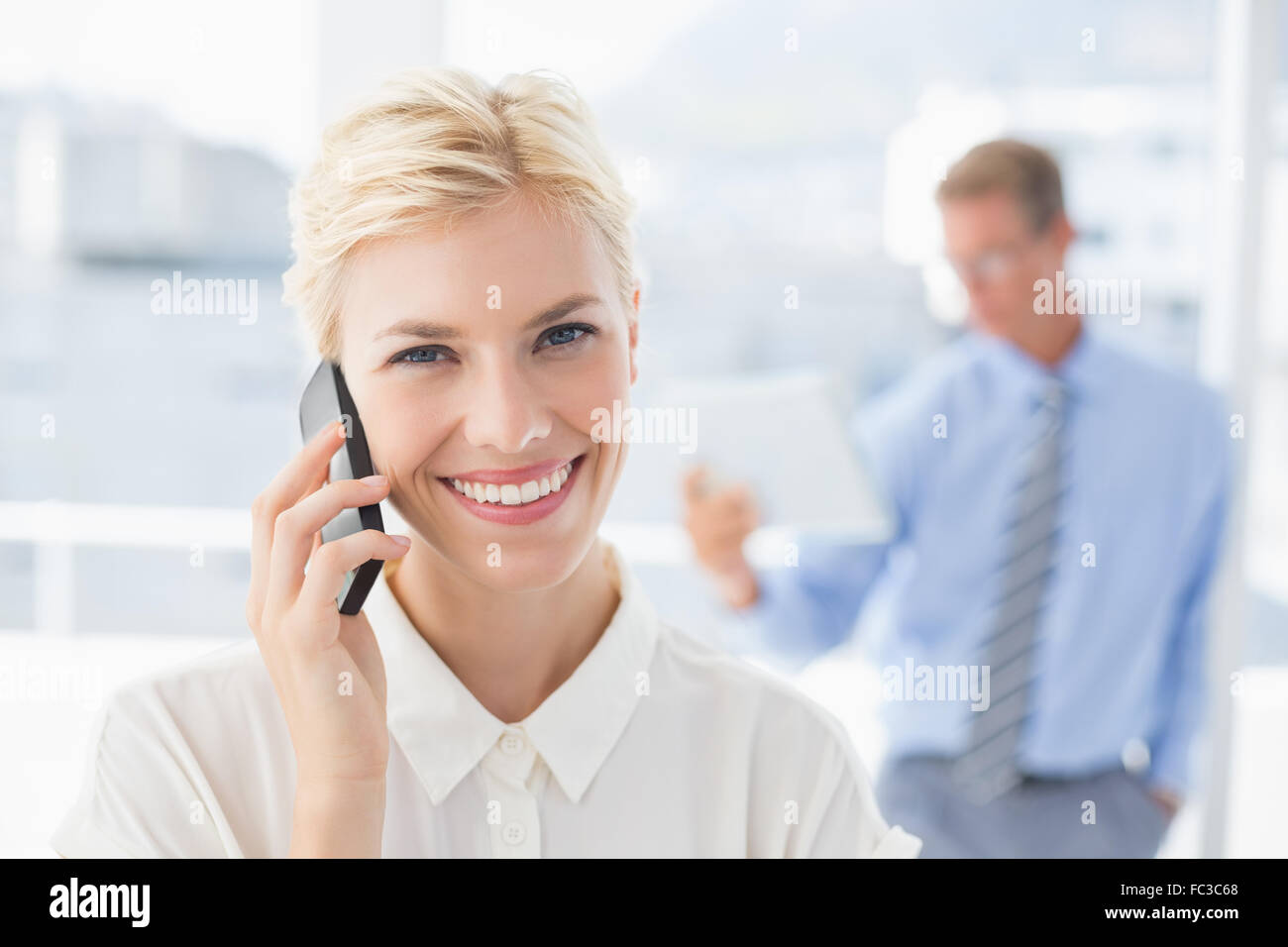 Businesswoman having a phone call avec un collègue en arrière-plan Banque D'Images