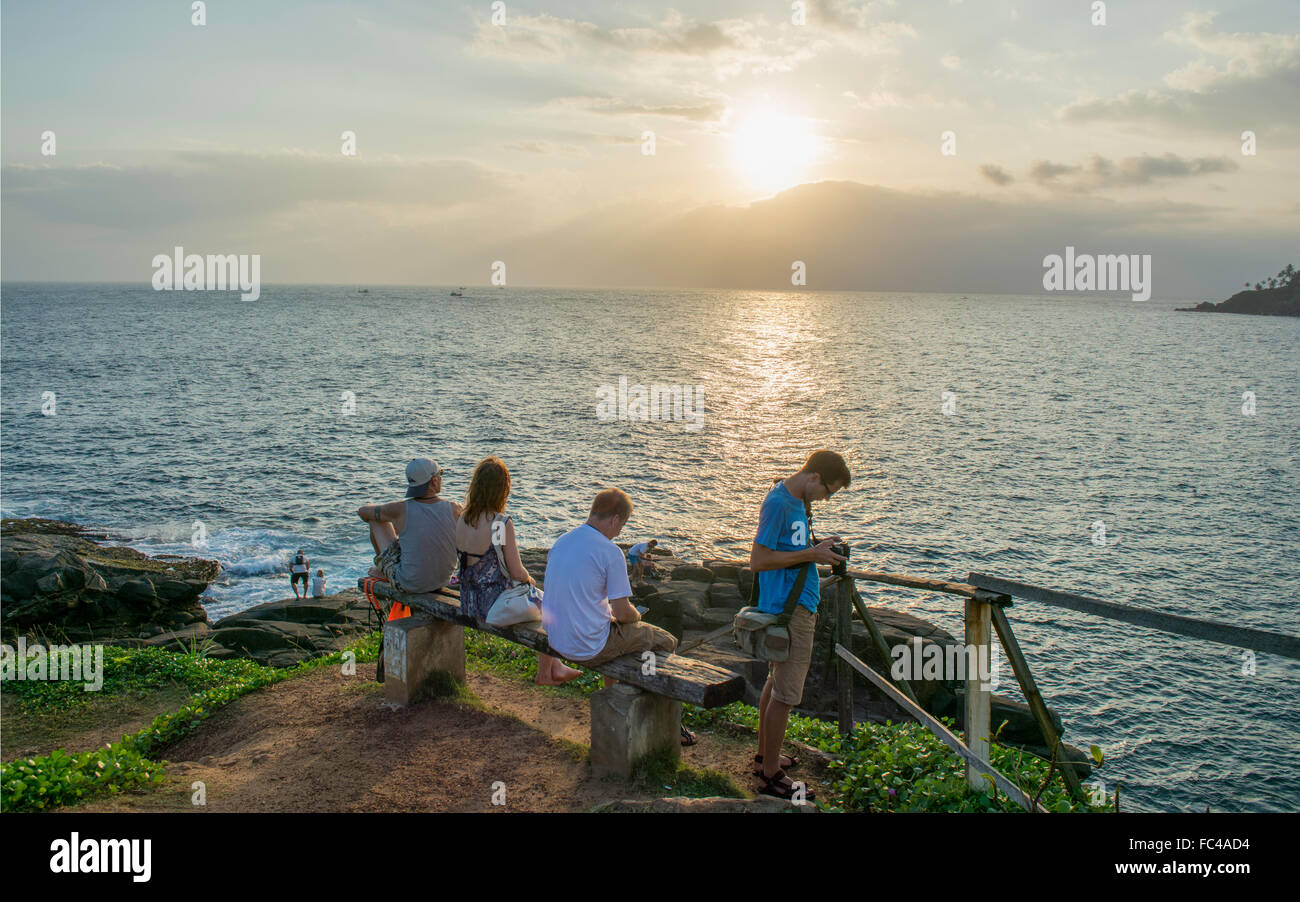 Les voyageurs en attente sur un banc sur une falaise pour prendre une photo du coucher de soleil en Mirrissa, Srilanka. Banque D'Images