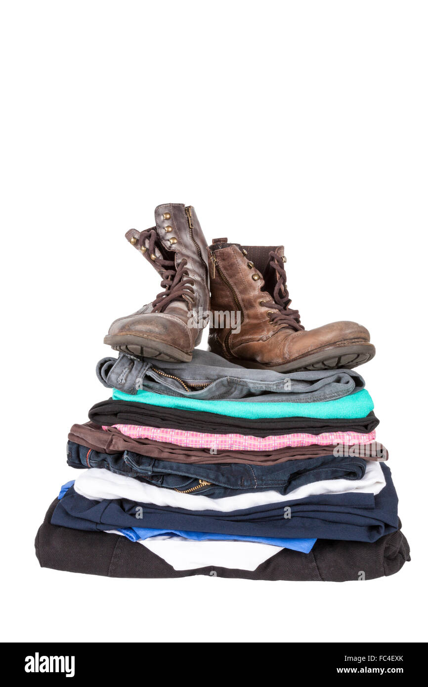 Paire de vieilles bottes en haut d'une pile de vêtements isolé sur fond blanc Banque D'Images