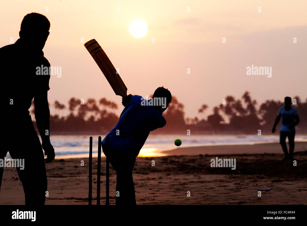 Garçon jouer au cricket au coucher du soleil sur la plage tropicale au Sri Lanka Banque D'Images