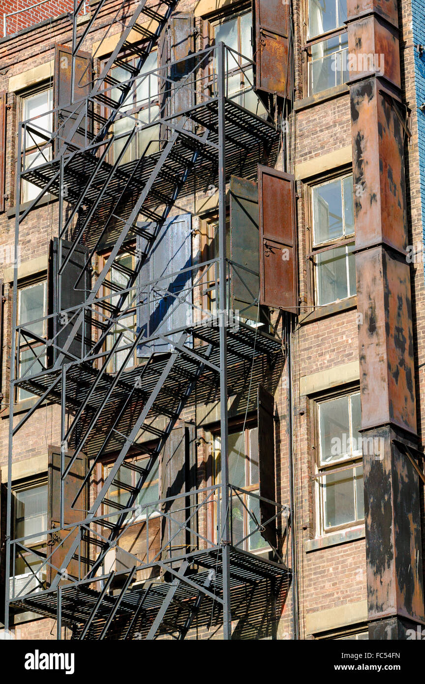 Un escalier de secours sur un vieux bâtiment de brique avec ses volets métalliques rouillées sur Bleeker Street à Soho, Manhattan, New York City Banque D'Images