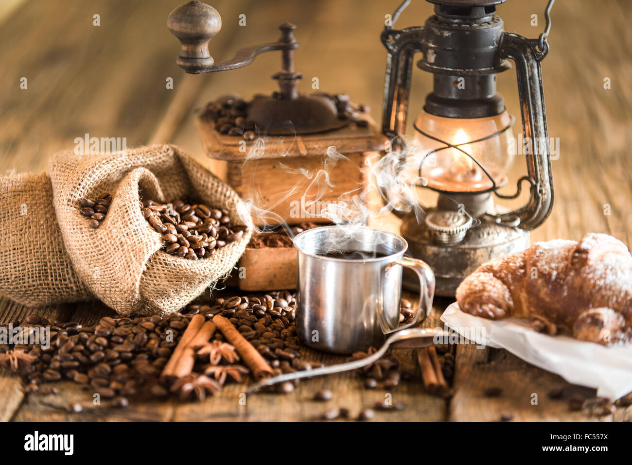 Les petit-déjeuner italien composé de café et de croissants, sur une table en bois avec une lampe au kérosène. Banque D'Images