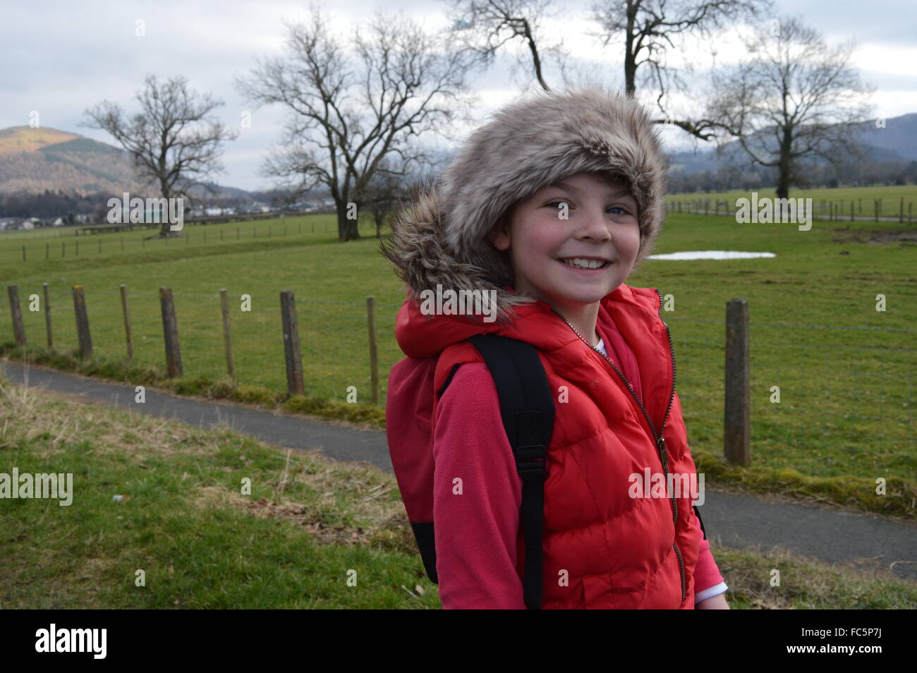 Fille dans un manteau rouge avec un chapeau de fourrure et le capot avec une toile de fond de la région du Lake district cumbria Banque D'Images