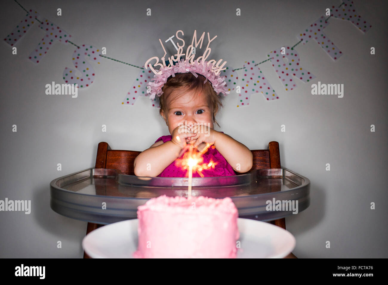Caucasian baby girl admiring birthday cupcake Banque D'Images