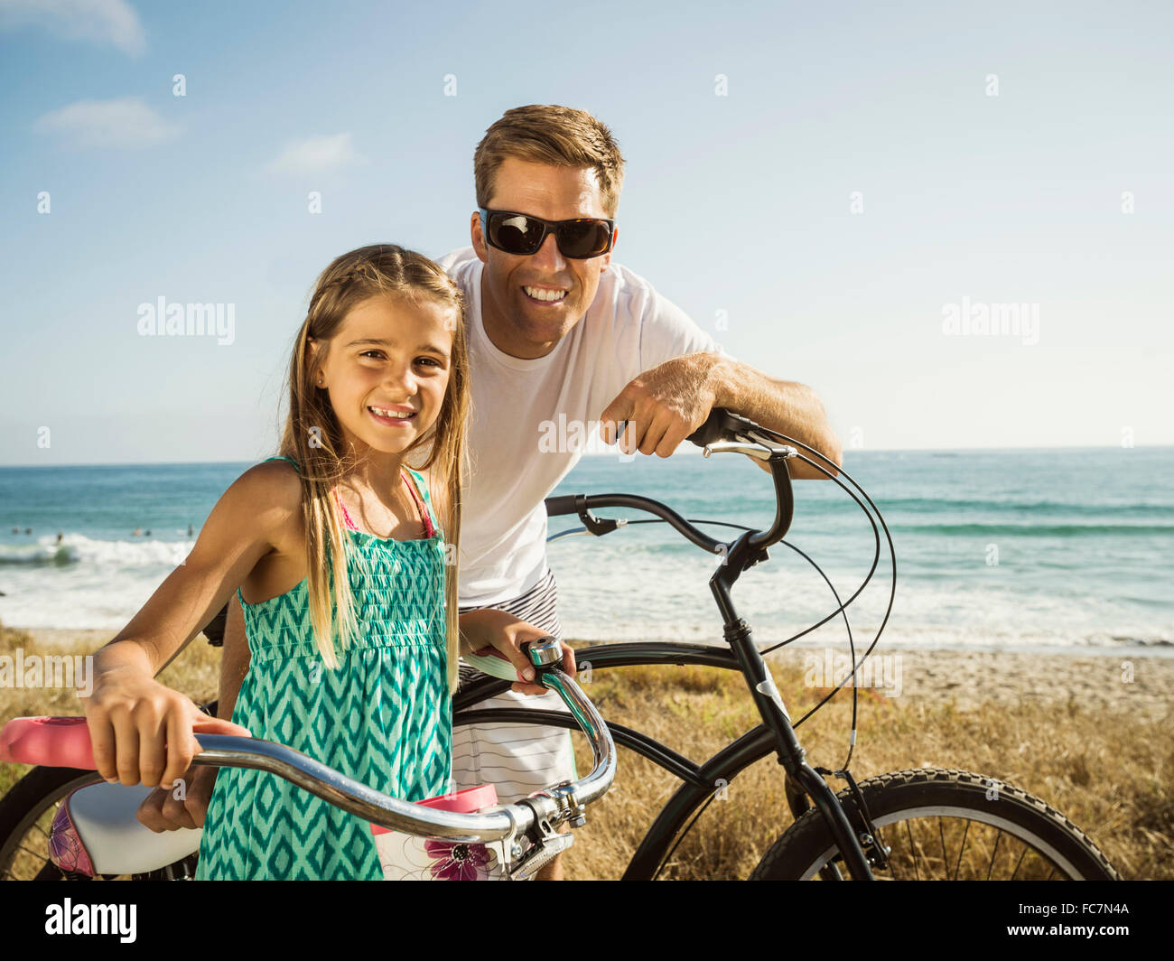 Caucasian father and daughter riding bicycles on beach Banque D'Images