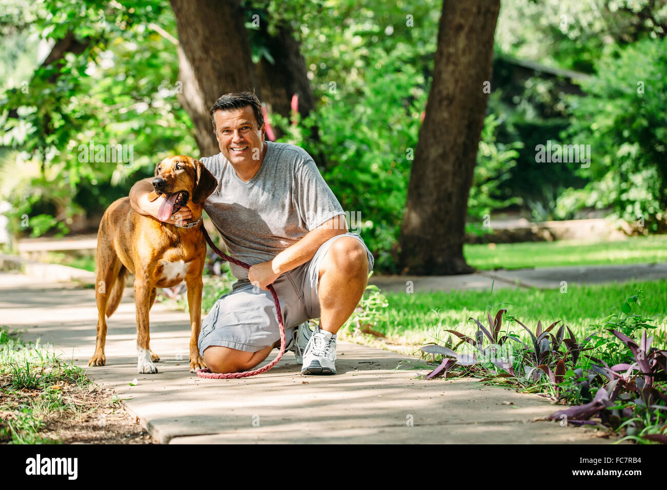 Caucasian man petting dog on sidewalk Banque D'Images