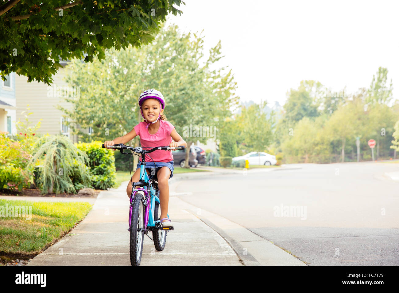 Mixed Race girl riding bicycle on sidewalk Banque D'Images
