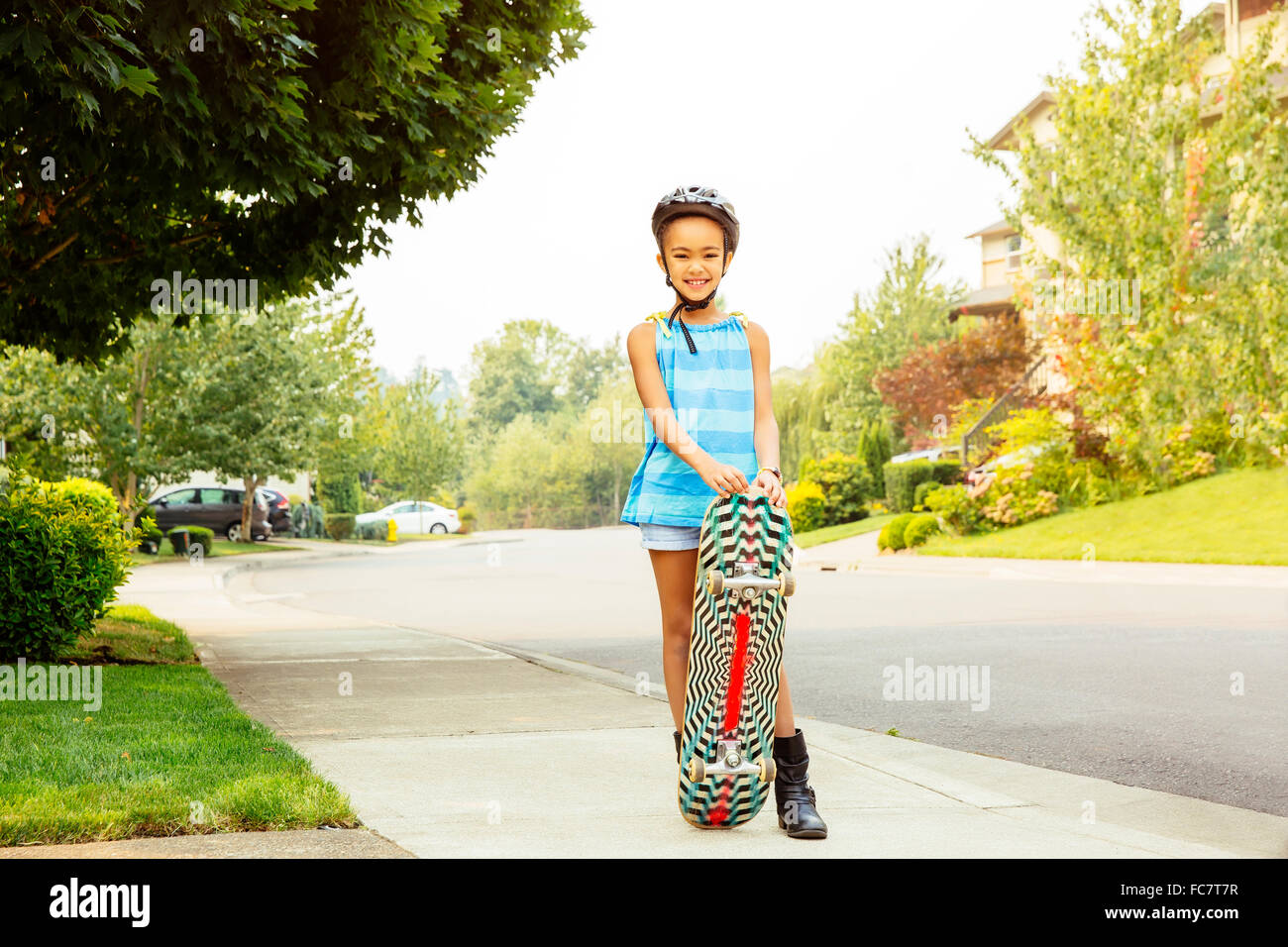 Mixed Race girl riding skateboard on sidewalk Banque D'Images