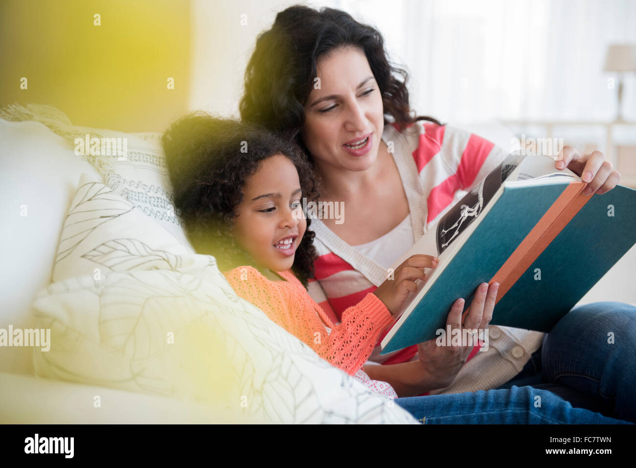 Mère et fille la lecture sur canapé Banque D'Images