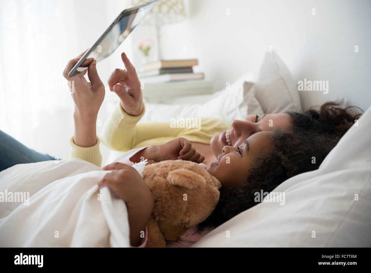 Mère et fille using digital tablet in bed Banque D'Images