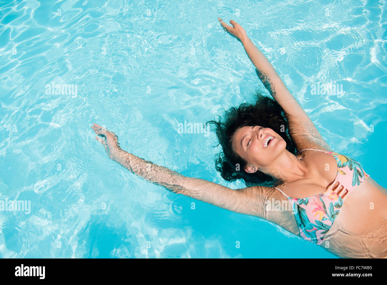 Caucasian woman floating in swimming pool Banque D'Images