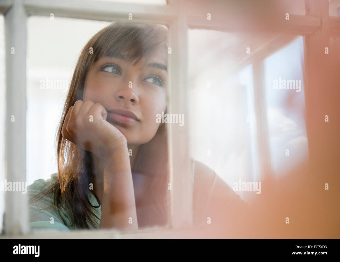 Mixed Race woman looking out window Banque D'Images