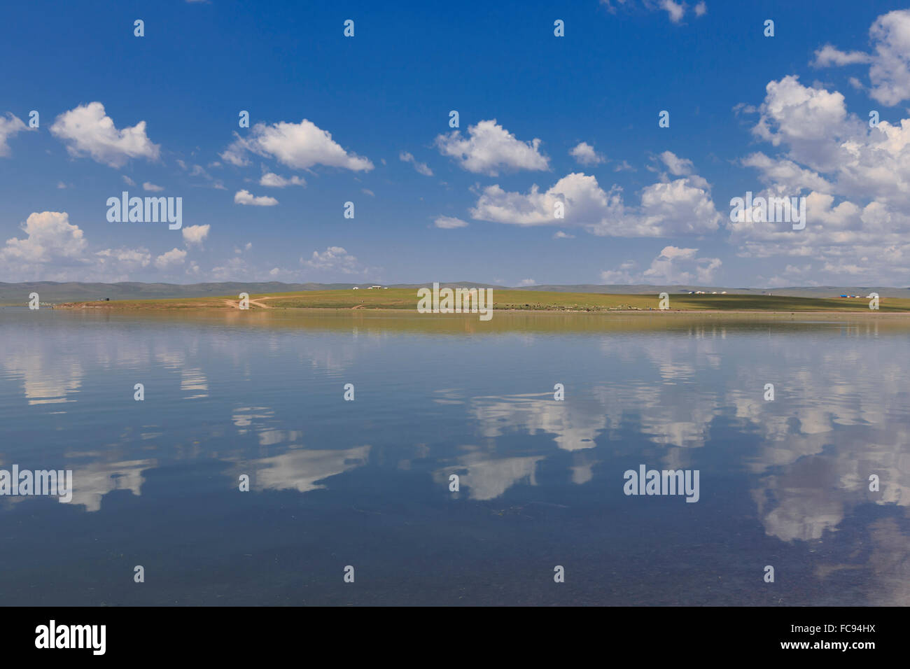 Fluffy nuages dans un ciel d'été bleu, qui se reflète dans un lac lointain, reflétée gers, Arkhangai, la Mongolie centrale, Asie centrale, Asie Banque D'Images