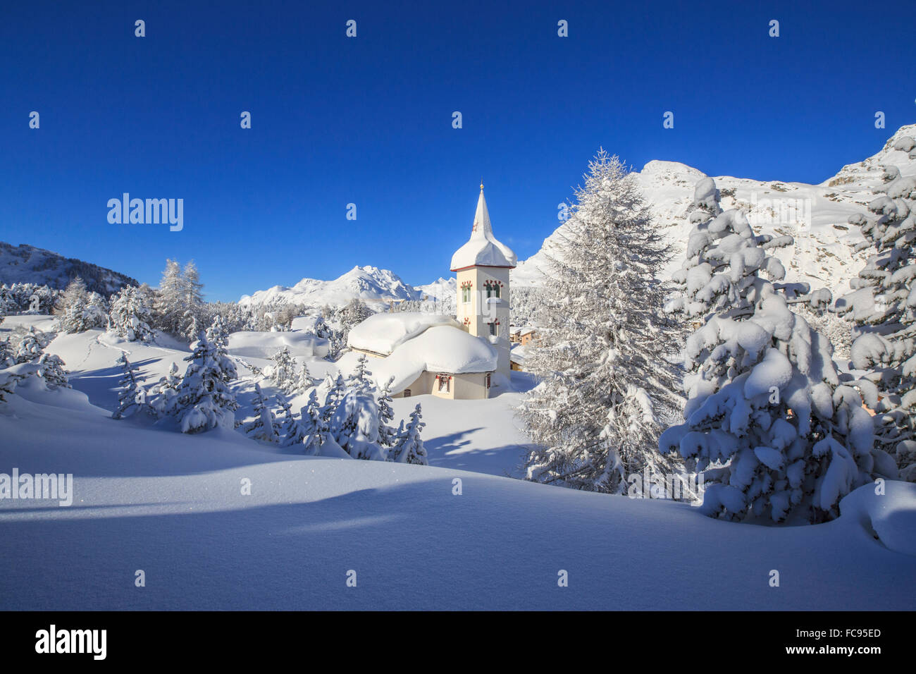 Le soleil d'hiver illumine le paysage de neige et de l'église typique, Maloja, Engadine, Canton des Grisons, Suisse Banque D'Images