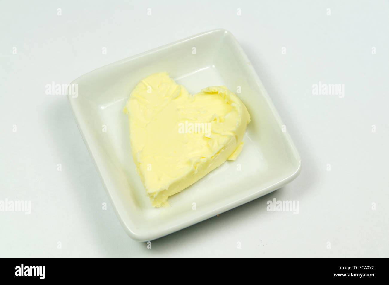 Le beurre en forme de cœur pat dans le plat. Banque D'Images