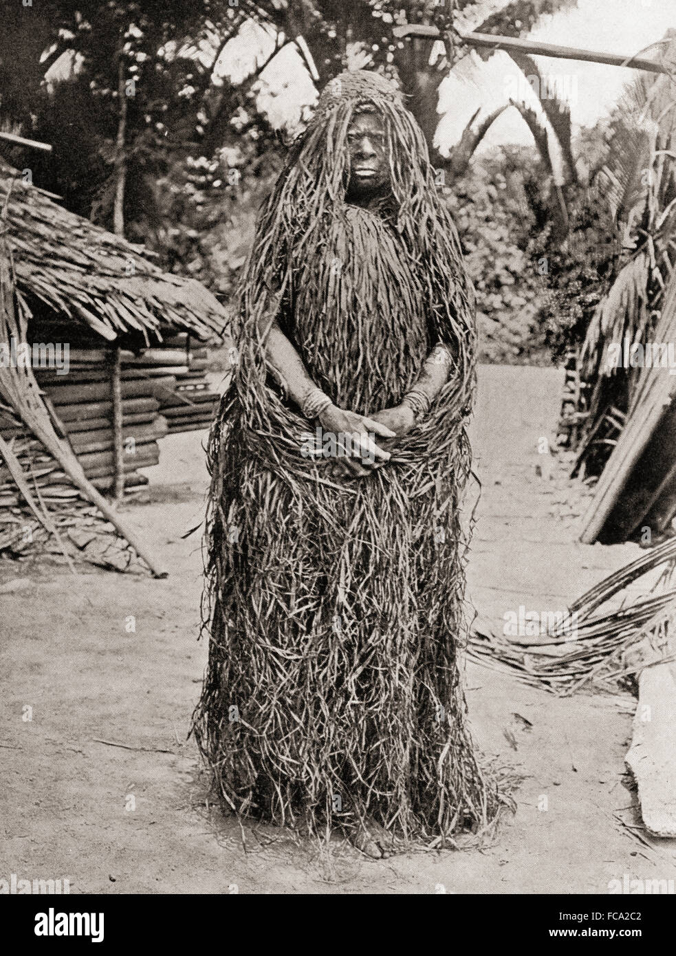 Femme portant un costume de deuil fait d'herbe, de la Mélanésie, de l'Océanie. Après la mort d'un homme sa femme fut enfermé pendant un certain temps. Elle enduit son corps dans la boue, poussaient de façon continue et seulement quitté son enclos au soir. Après une photographie du xixe siècle Banque D'Images