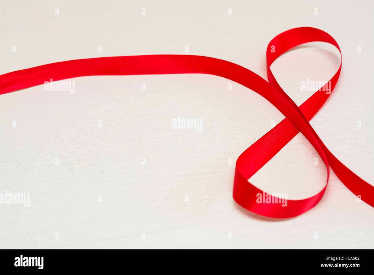 Bonne Journée de la femme. Ruban cadeau rouge en forme de 8 chiffres sur fond de bois blanc. Selective focus Banque D'Images