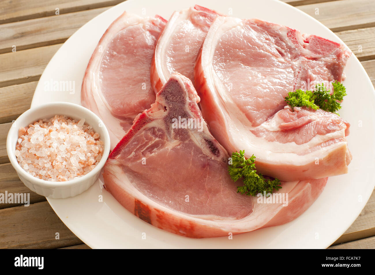 Côtelettes de porc frais sur la plaque avec du sel de roche Banque D'Images