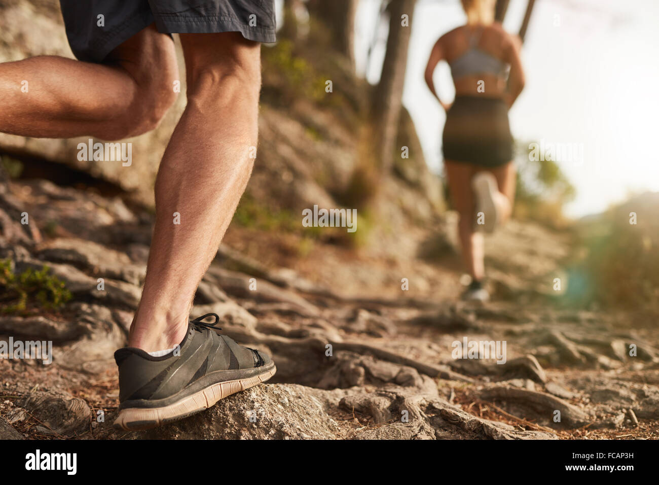 De gros plan homme pieds courir à travers un terrain accidenté. Course cross-country avec l'accent sur les jambes du coureur. Banque D'Images