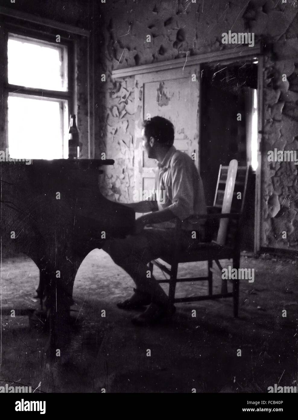 Longueur totale du pianiste jouant du piano dans la maison abandonnée Banque D'Images