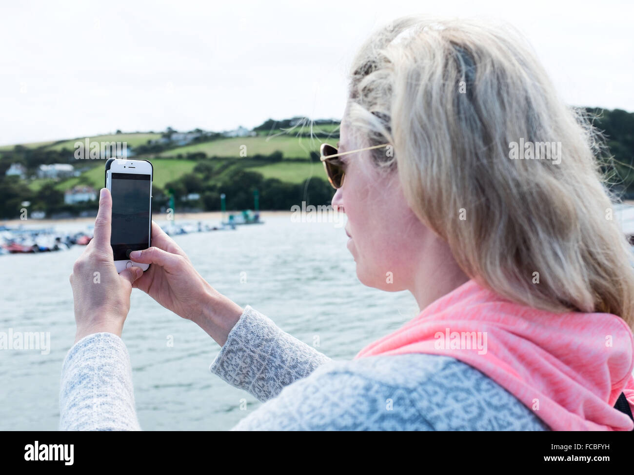 Femme de prendre une photo avec son téléphone portable des bateaux et de la mer Banque D'Images