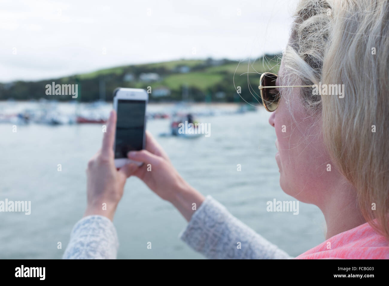 Femme de prendre une photo avec son téléphone portable des bateaux et de la mer Banque D'Images