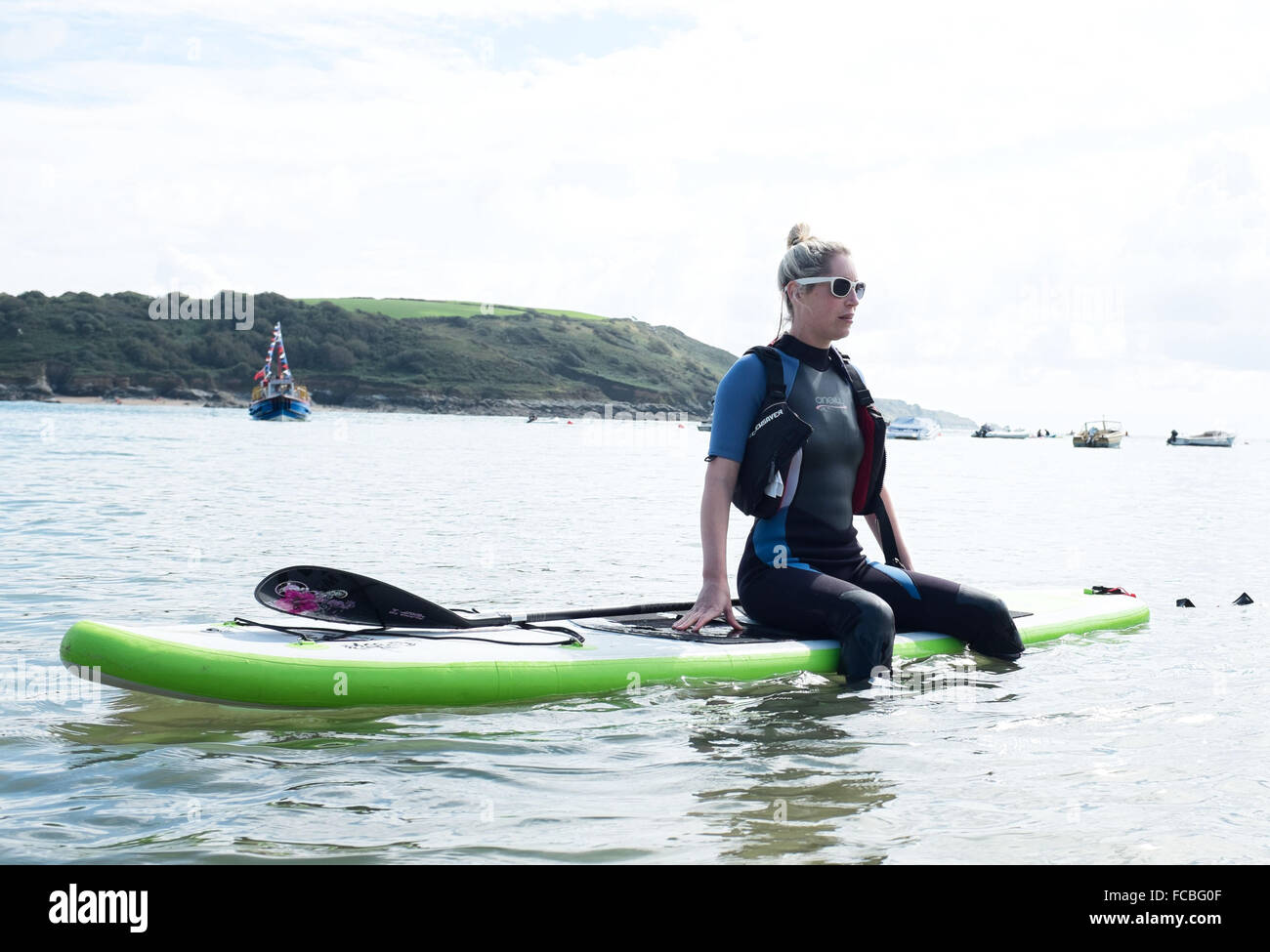 Femme assise sur un paddle board dans la mer à de graves Banque D'Images