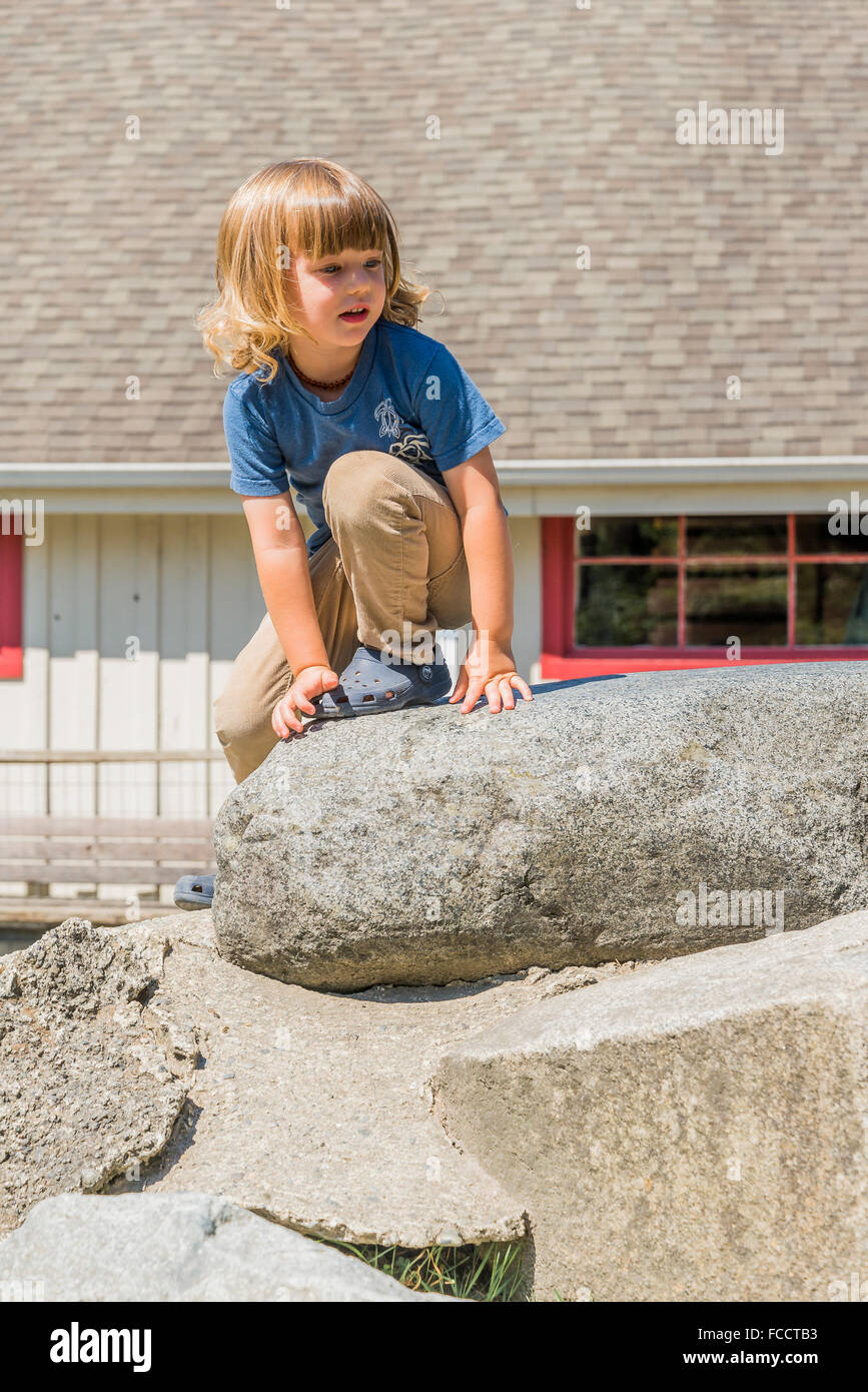 Jeune garçon escalade sur le rock pile Banque D'Images