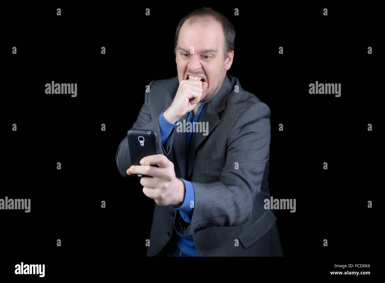 Jeune homme costume gris foncé téléphone mobile en colère Banque D'Images