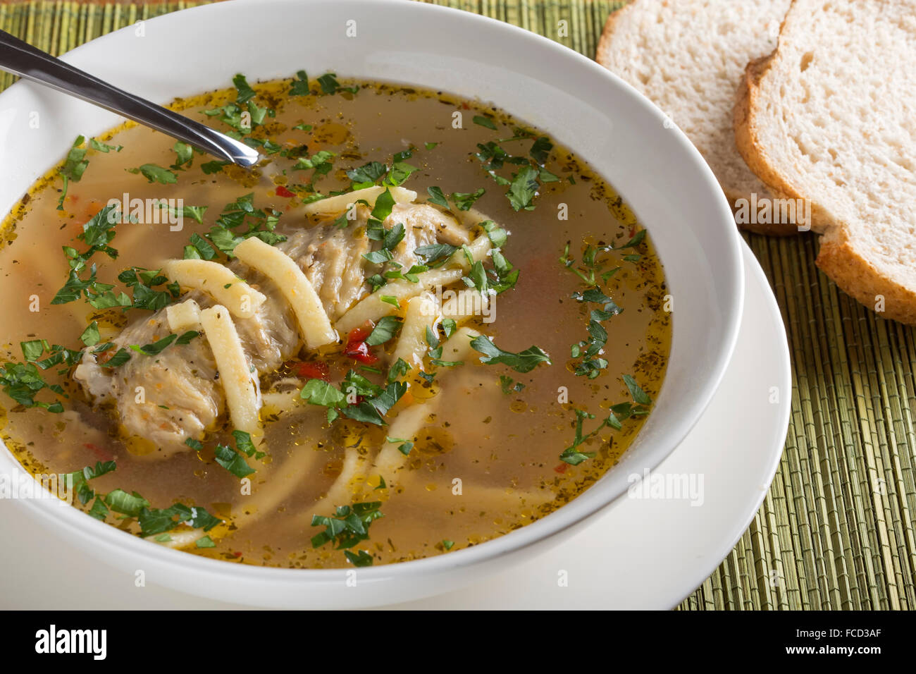 Soupe au poulet fait maison dans un bol blanc avec cuillère et du pain Banque D'Images