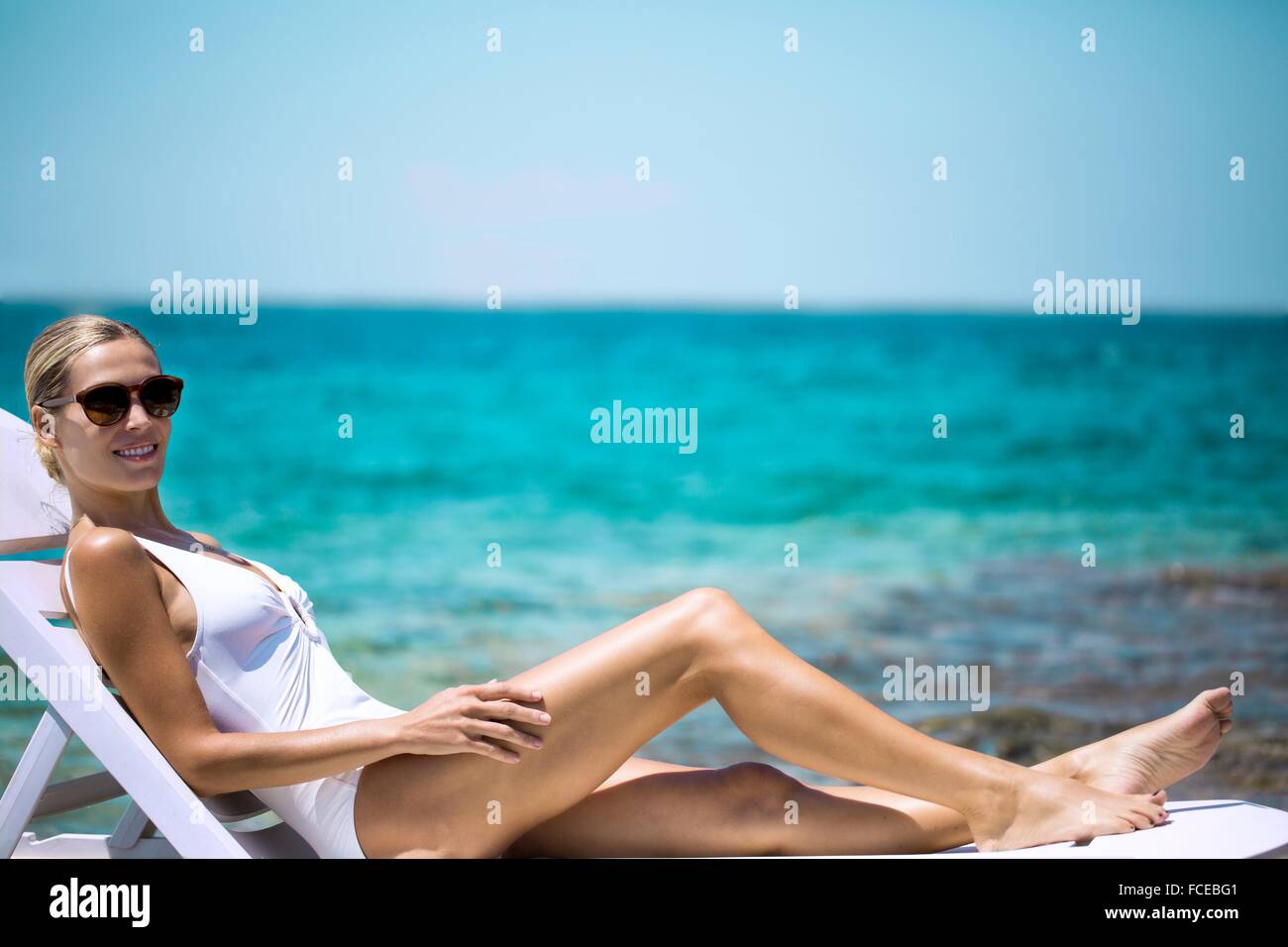 Jeune femme en train de bronzer sur un transat Banque D'Images